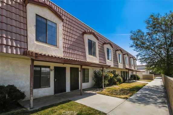 Front view of a two-story townhouse with a tile roof and multiple entry doors.