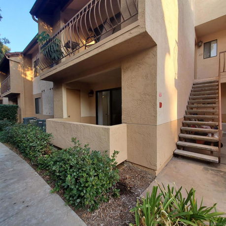 Front view of a two-story apartment building with balconies and exterior stairs.