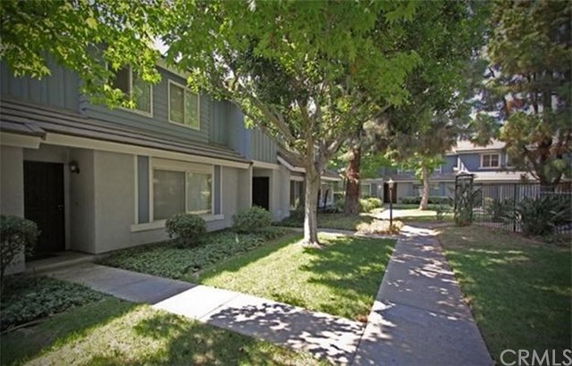 Front view of a two-story residential building with pathway and trees.