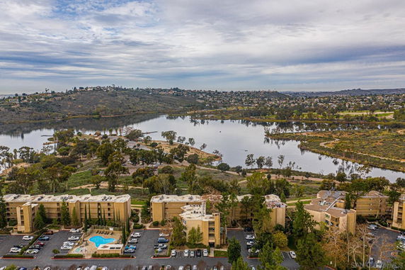 Panoramic view of buildings and a large body of water surrounded by hills and vegetation.