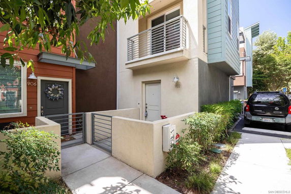 Front view of a modern multi-story townhouse with balconies and a gated entrance.