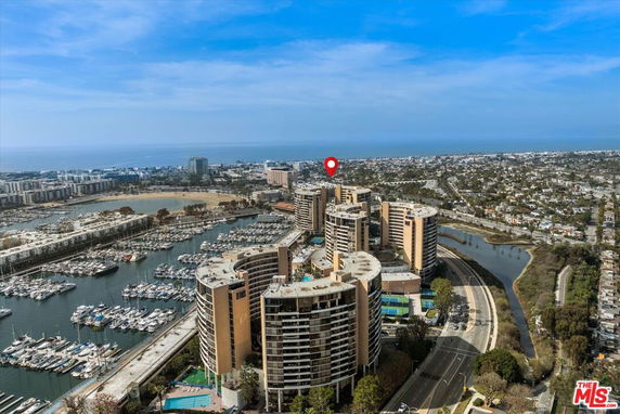 Aerial view of a waterfront area with large buildings and numerous docks filled with boats.