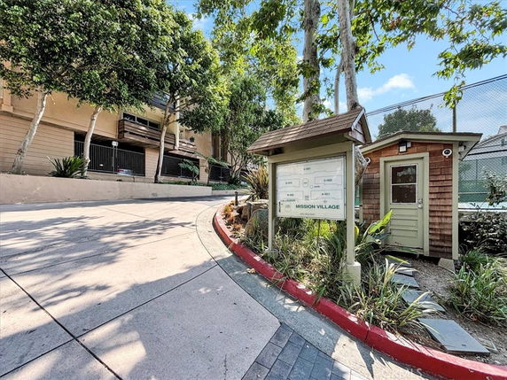 Pathway leading to residential complex with a kiosk and small building.