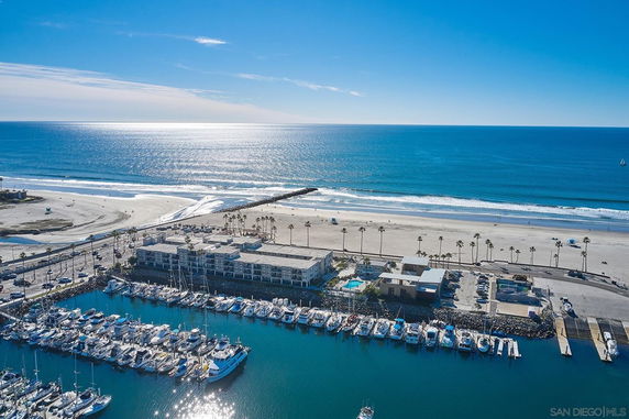 Panoramic view of a coastal area with buildings, a marina, and the ocean.