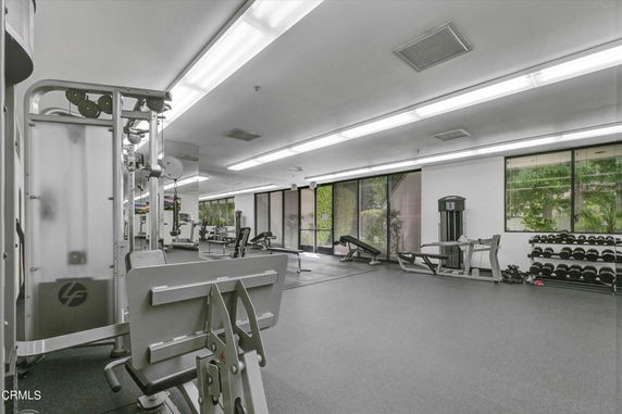 Interior view of a gym facility with exercise equipment and large windows.