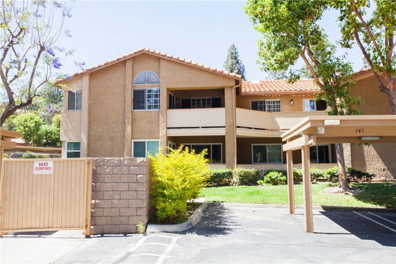 Front view of a two-story apartment building with a tiled roof and covered parking.