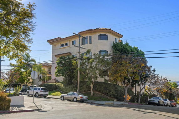 Front view of a multi-story residential building on a sloped street.