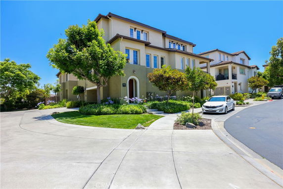 Front view of a multi-story house with a well-maintained garden and driveway.