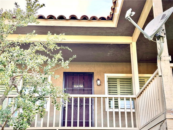 Front view of a building with a balcony, windows, and a satellite dish.