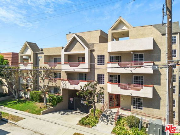 Front view of a multi-story apartment building with multiple balconies and pitched roofs.