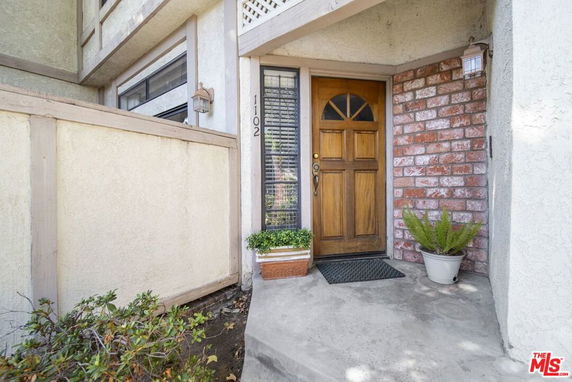 Main entrance of a house with a wooden door and brick accents.