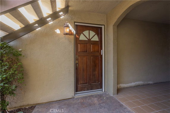 Front view of an entrance door with an arched design and exterior wall light.