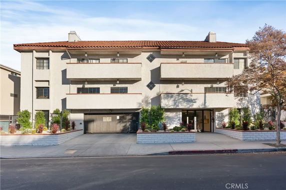 Front view of a multi-story building with balconies and a tile roof.