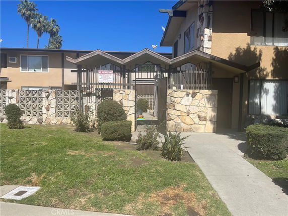 Front view of a multi-story building with stone accents and fenced entryway.