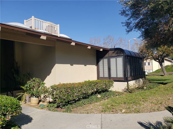 Front view of a house with a rooftop deck and a sunroom extension.