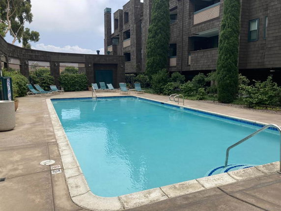 Outdoor swimming pool adjacent to a multi-story building.