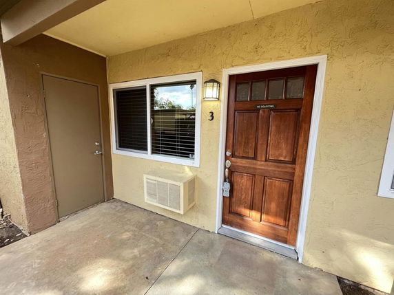 Front view of a building with a brown wooden door and a window.