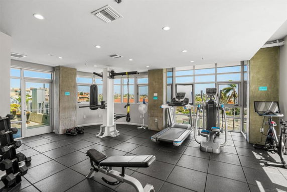 Fitness room with exercise equipment and large windows.