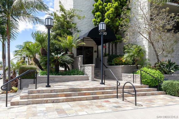 Front view of a building entrance with stone steps and plants.