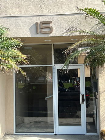 Front view of a building entrance with a glass door and the number 15 above it.