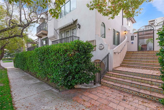 Front view of a multi-story building with decorative tile steps and gated entrance.