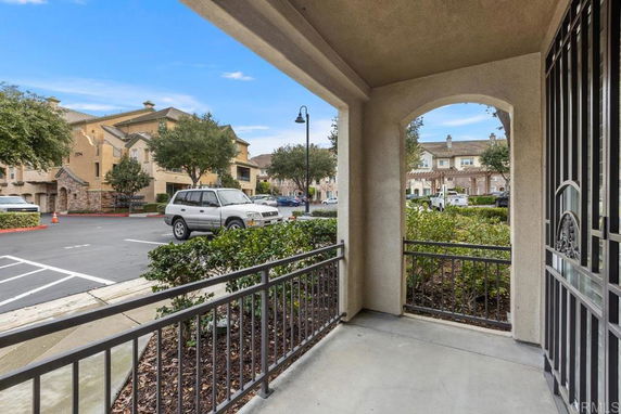 View from a porch looking towards a residential area with multiple houses and parked cars.
