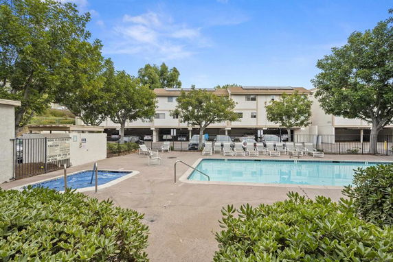 Outdoor swimming pool with lounge chairs and surrounding trees.