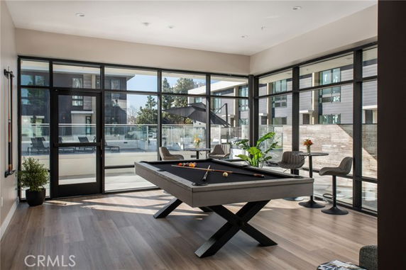 Room with a pool table and large windows in a recreational area.