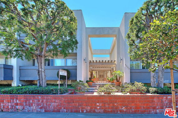 Front view of a multi-story building with a prominent entrance and surrounding trees.