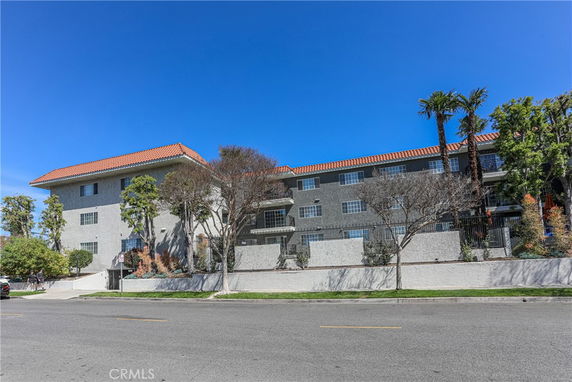 Front view of a multi-story residential building with a red-tiled roof.