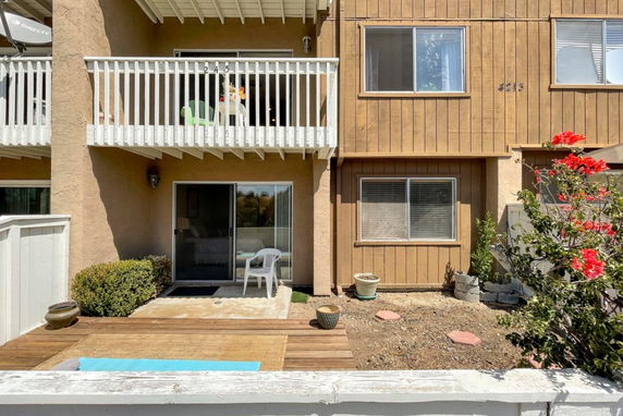 Front view of a two-story house with a balcony and a sliding glass door.