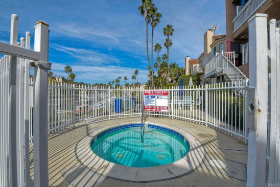 Outdoor swimming pool area with safety fence and nearby buildings.