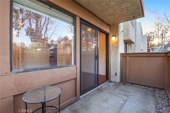 Outdoor patio area with sliding glass door and small glass table.