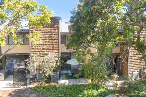 Front view of a two-story townhouse with a shingle exterior and patio areas.