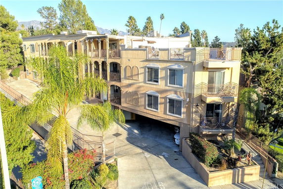 Front view of a multi-story building with balconies and a parking area underneath.