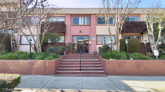 Front view of a multi-story building with stairs leading to the entrance.