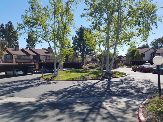 Outdoor parking area with trees and multiple residential buildings.