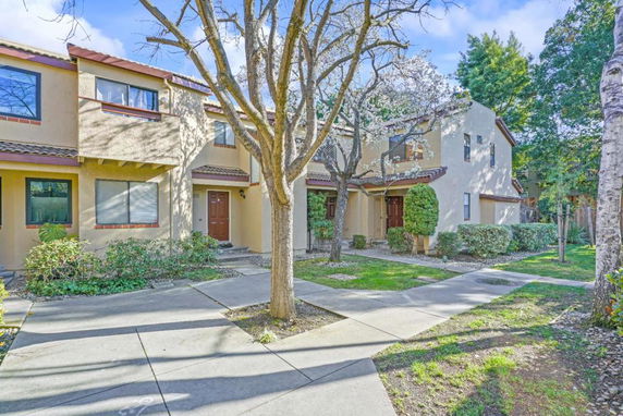 Front view of a two-story townhouse with a small garden and paved walkway.