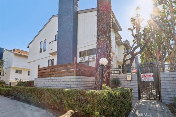 Front view of a multi-story residential building with a gated entrance.