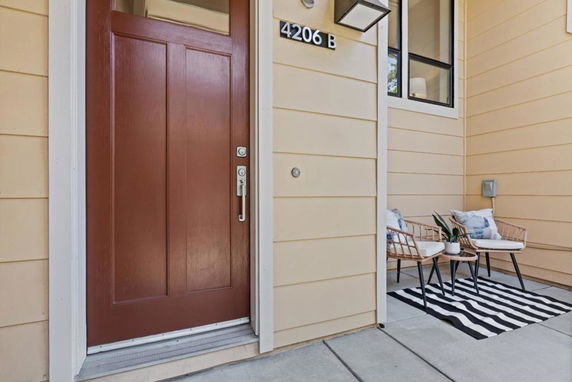 Front view of a house entrance with a brown door and small seating area.