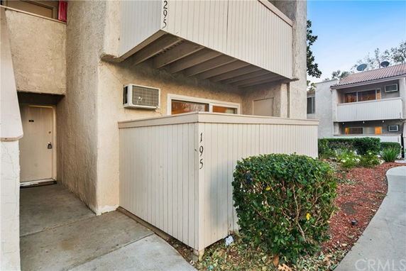 Front view of a condominium-style apartment with balconies and an air conditioning unit.