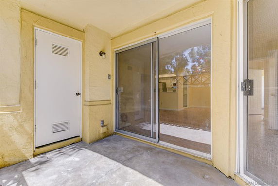 Outdoor patio area with sliding glass doors and a closed utility door.