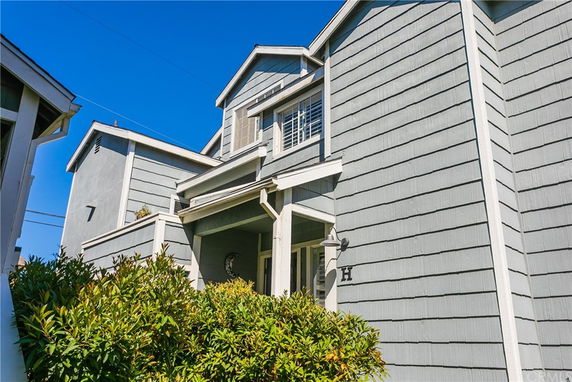 Front view of a two-story house with a porch and gray siding.