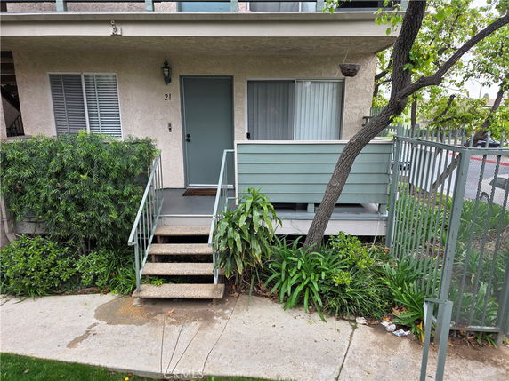 Front view of a two-story apartment building with a staircase and railing leading to the entrance.