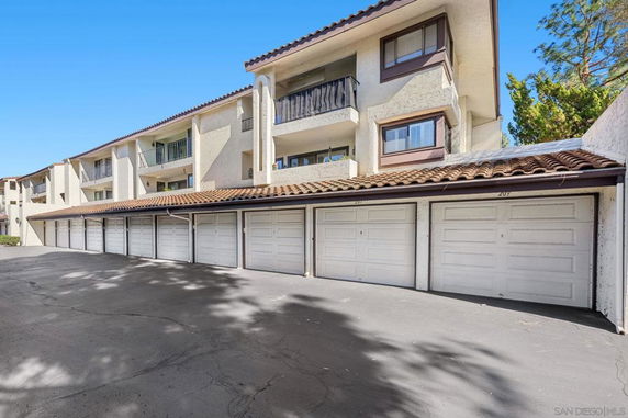 Outdoor parking area with multiple garage doors beneath a multi-story building.