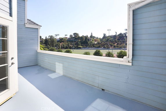 Rooftop view with light blue walls and sports fields visible in the background.