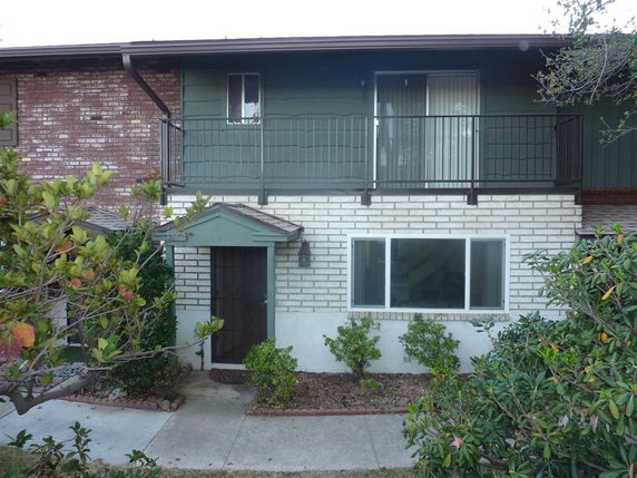 Front view of a two-story house with a balcony and brick exterior.