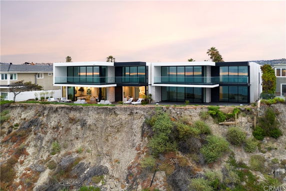 Front view of a modern two-story house on a cliff with large glass windows.