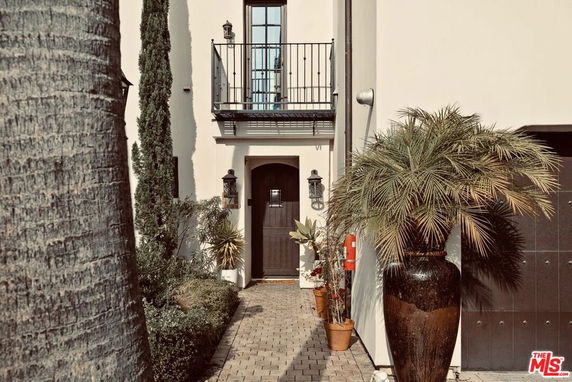 Front view of a house with a small balcony and potted plants.
