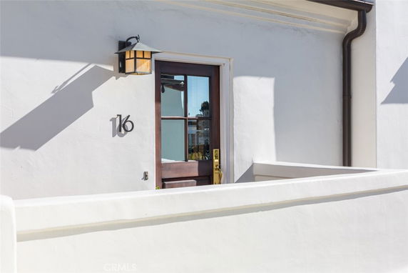 Front view of a house entrance with a wooden door and white walls.